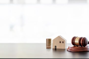 Real estate sale auction concept - gavel, house model and stack of coins on wooden table,